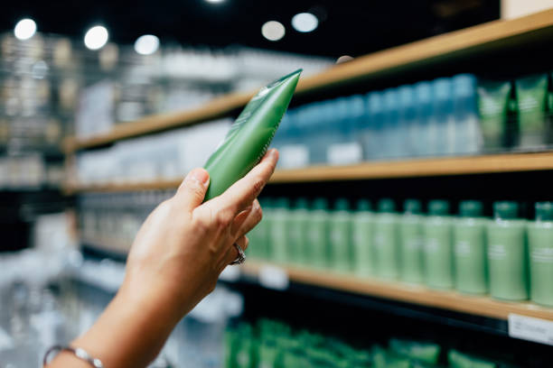 A woman holding a tube of a hand cream while shopping at a store.